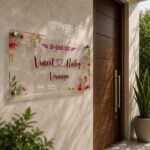 Floral Vineet and Ruby couple name plate mounted on a wall beside a wooden main door