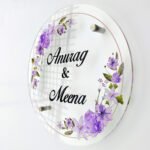 Round Anurag and Meena lavender floral acrylic name plate angled on a white background