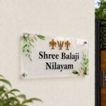 Transparent Shree Balaji Nilayam devotional name plate mounted on a home exterior wall near the gate