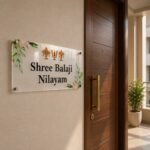 Transparent Shree Balaji Nilayam name plate mounted beside a wooden main door - devotional acrylic design for home